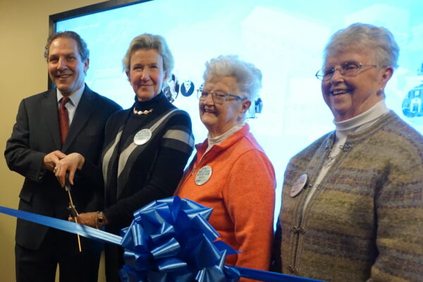 From left: Joel Seligman and Nancy Karch lead a ribbon cutting ceremony with Pat Reilly and Joan Stewart in front of the interactive historical timeline.