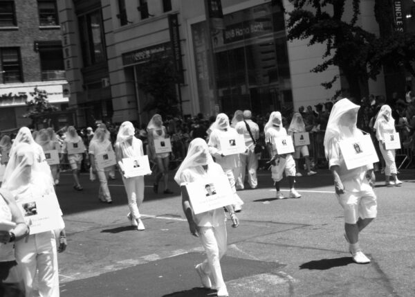 Shrouded participants bring uncharacteristic silence to spectators as they pass, each adorned in the name and photo of an Orlando Pulse nightclub victim. It was a poignant, somber moment on a day of celebration.
